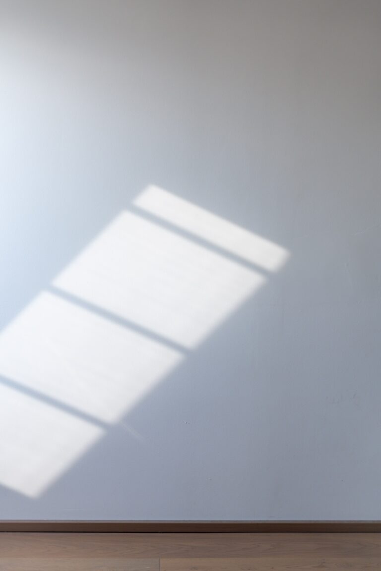 Eine weiße Wand mit dem Schattenspiel eines Fensters